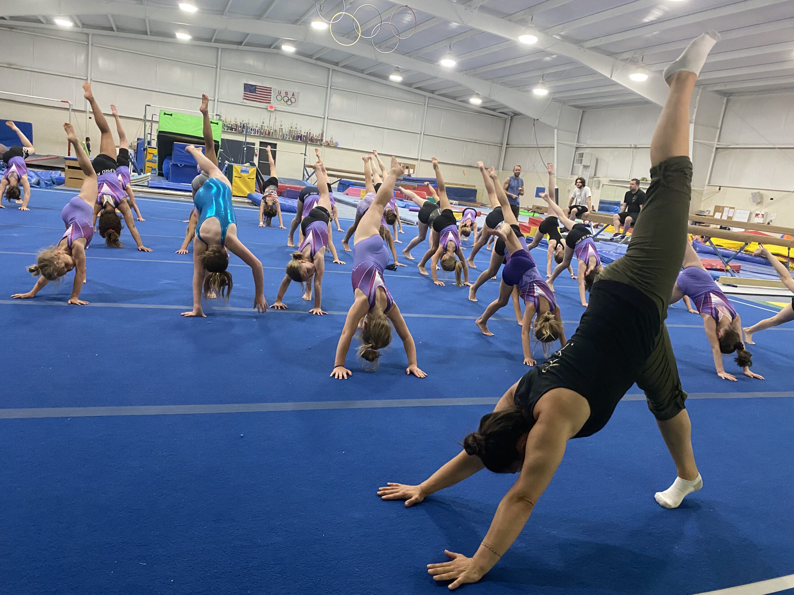 Dr. Shira coaching young gymnasts on the floor